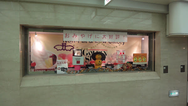 a store window display includes a stack of three jack-o-lanterns wearing a witches' hat and an image of a bat in the background